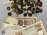a pile of old coins and a bank note on a table