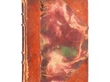 un vieux livre à la couverture rouge posé sur une surface blanche