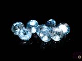 un gros plan sur trois diamants de couleur topaze bleue posés sur une surface noire