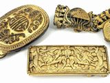 four pieces of gold jewelry on a white surface