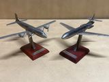une paire de maquettes d'avions en argent posées sur des socles en bois, sur une table