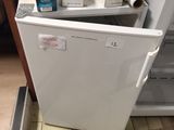 a small white refrigerator in the corner of a kitchen