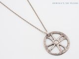 Le collier est en argent et présente un motif circulaire.