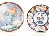 two plates with designs of flowers and birds on them on a white surface