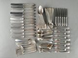 a lot of silver spoons and forks laid out on a table