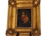 painting of a woman holding a child in a gold frame on a stand