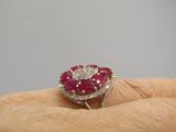 une photo représentant la main d'une femme tenant une bague sertie d'un diamant et d'un rubis