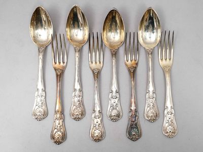 six cuillères en argent et une fourchette sont alignées sur une table