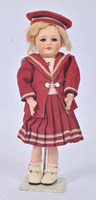 une poupée qui porte une robe rouge et un chapeau