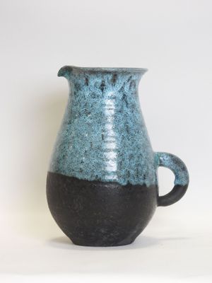 a blue and black vase sitting on a white surface