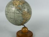 a small globe on a wooden stand with a white background