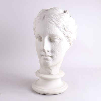 une sculpture blanche représentant la tête d'une femme, posée sur un socle
