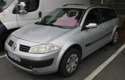 a silver car parked in a parking lot next to a white van