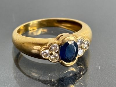 an image of a close up of a gold ring with a sapphire and diamonds