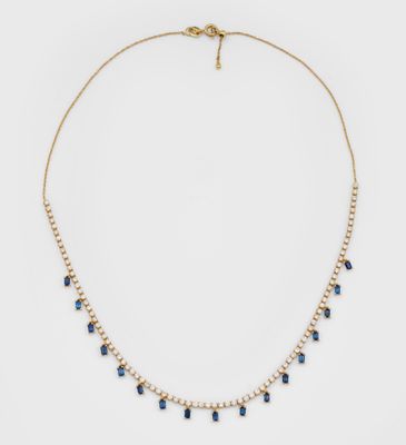 un collier en or orné de cristaux bleus et de perles sur fond blanc