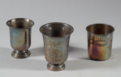 trois tasses en argent posées l'une à côté de l'autre sur une surface blanche