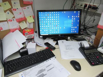 a desk with a computer, keyboard, calculator, and other office supplies on it