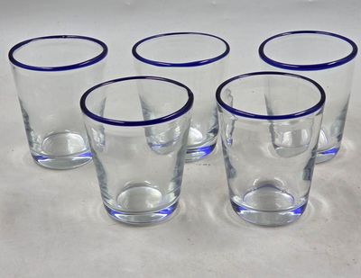 six verres aux bords bleus sont alignés sur une surface blanche