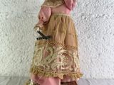 une figurine représentant une femme vêtue d'une robe rose et d'un chapeau