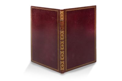 un vieux livre à la couverture rouge posé sur une surface blanche