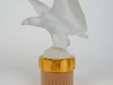 an image of a bottle of perfume with a bird figurine on top