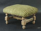 un petit repose-pieds surmonté d'un coussin vert