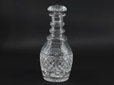 a clear glass decanter with a stopper on a black background