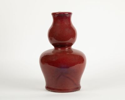a red vase that is sitting on a white surface