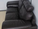 a black leather couch sitting in a corner of a room