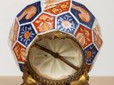 a small vase with a clock on it on a table