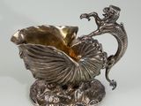 a silver vase with a dragon and a shell on it