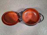 pair of copper colored pots with handles on a table