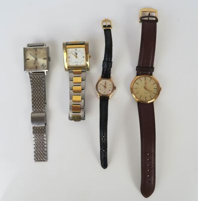 trois montres et une montre-bracelet sont posées sur une surface blanche