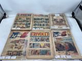 Plusieurs bandes dessinées anciennes sont exposées sur une surface blanche