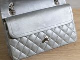 a person holding a silver purse on a wooden table