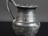 un vieux vase en argent posé sur une table noire