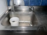 a sink with a bucket in it and a faucet in the sink