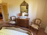 une chambre à coucher avec un lit, une commode, une chaise et un miroir