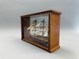 une petite maquette de bateau en bois exposée dans une vitrine