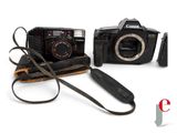 two cameras sitting next to each other on a white surface