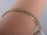 Quelqu'un porte un bracelet en or orné d'un motif.
