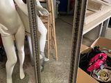 un mannequin debout près d'un miroir dans une pièce