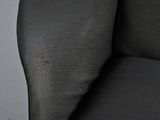 a close up of a black chair with a brown spot on the arm
