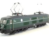 a green train that is on the tracks on a white surface