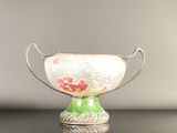 a green and white vase with a red flower on it