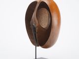 wooden sculpture of a hat on a metal stand on a white background