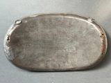 an old silver plate sitting on top of a table next to a knife