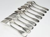 six cuillères en argent sont disposées en ligne sur une surface blanche