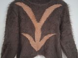 un pull marron orné d'un motif orange et blanc, suspendu à un cintre