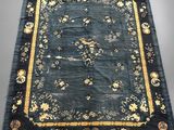 un tapis oriental noir et doré orné d'oiseaux et de fleurs